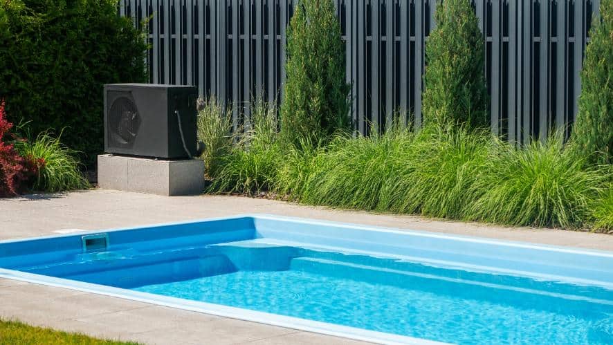 a black heat pump positioned near the edge of a rectangular swimming pool